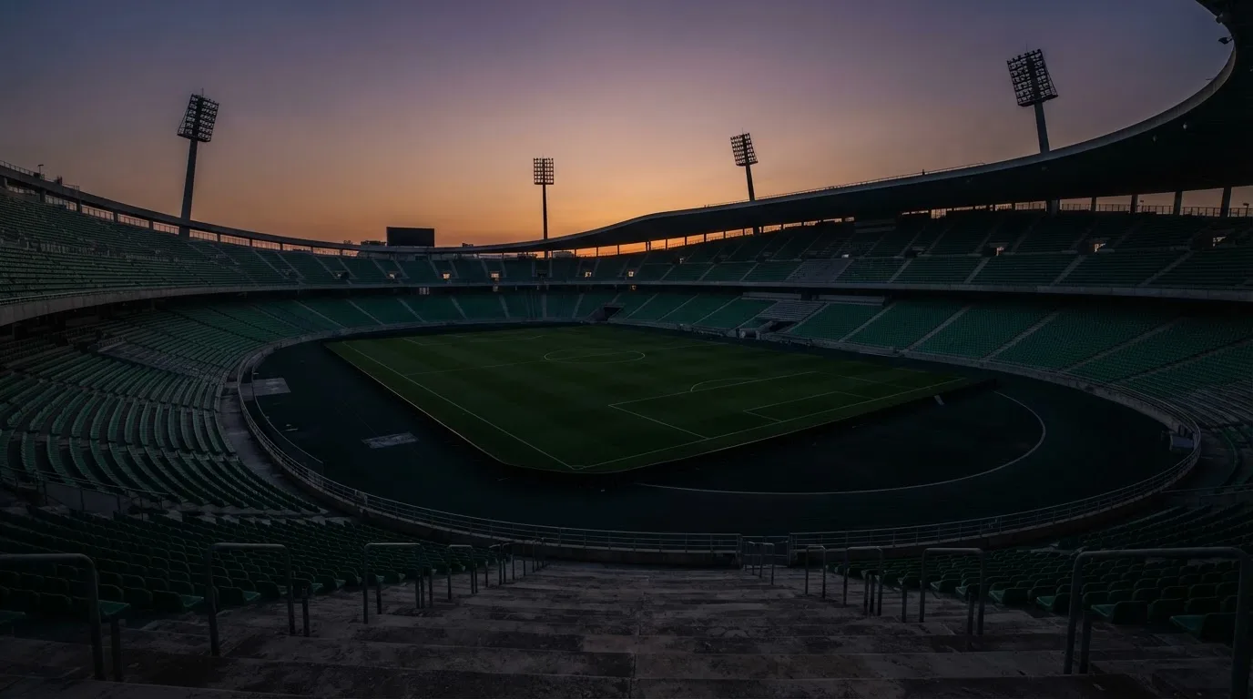 An empty football stadium with floodlight masts at dusk