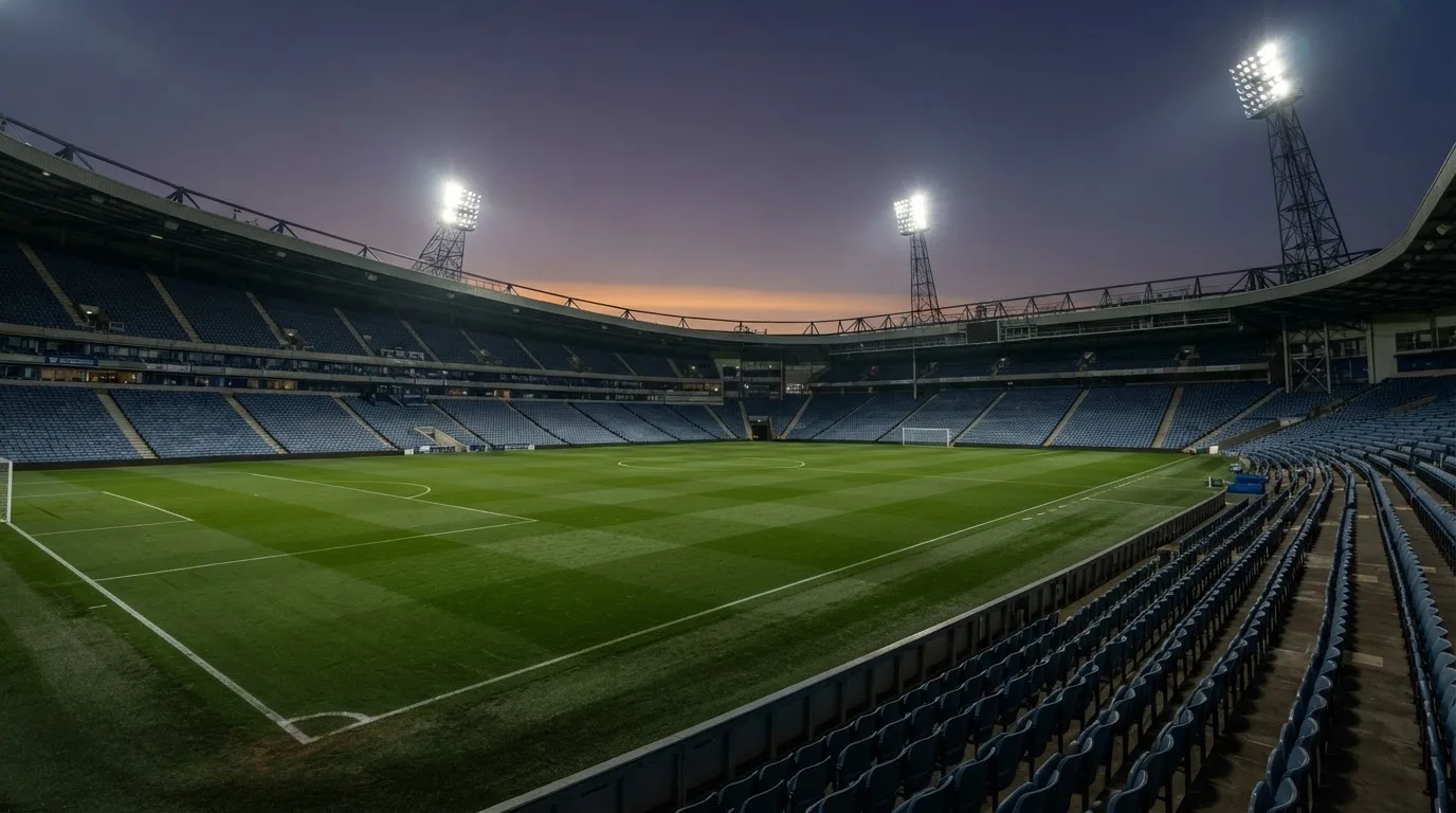 An empty football stadium with floodlight masts at dusk