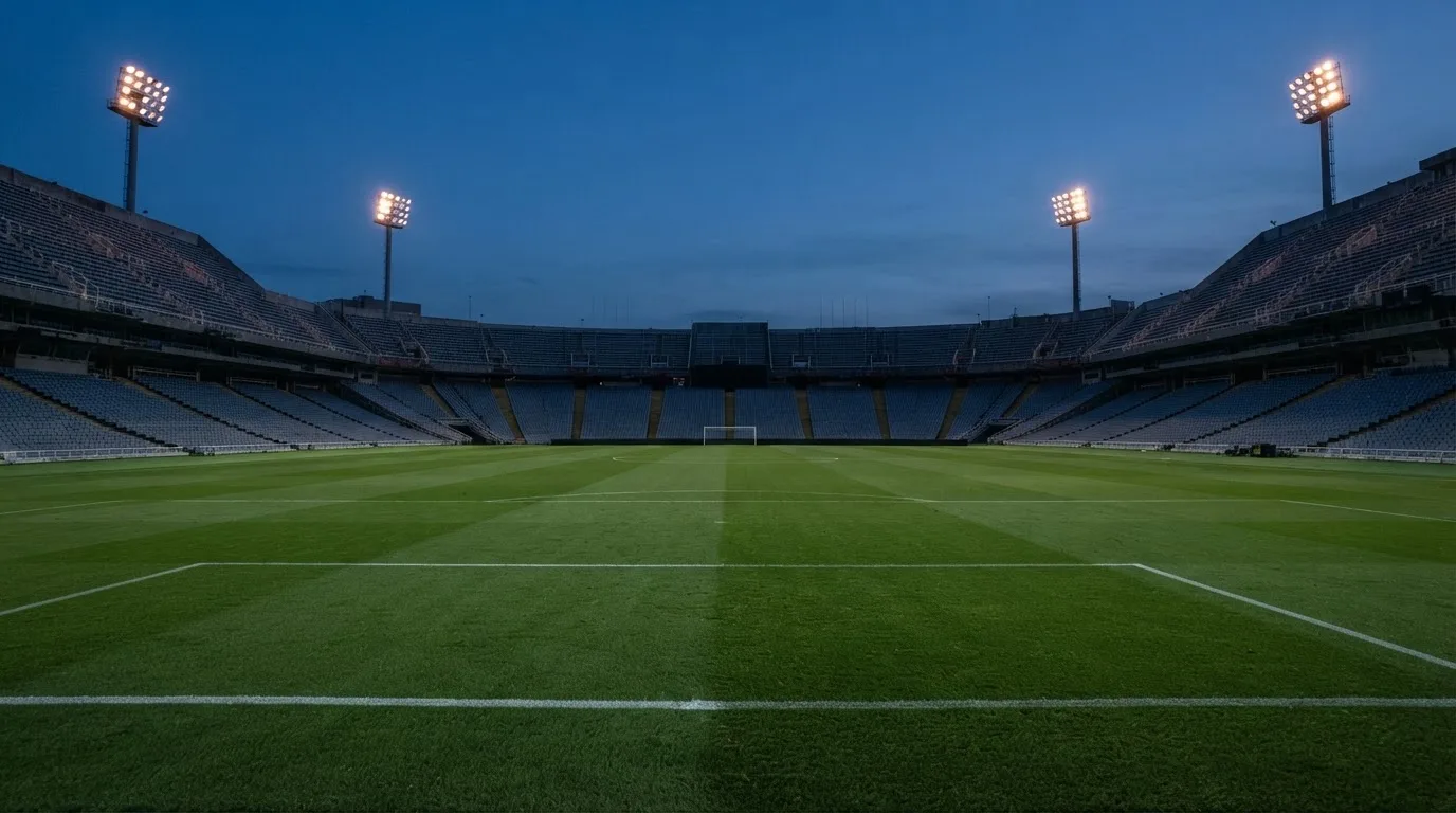 An empty football stadium with floodlight masts at dusk