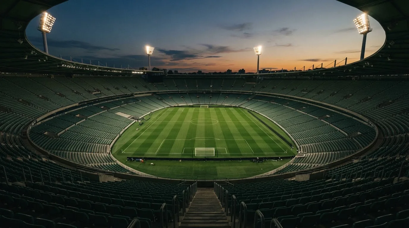 An empty football stadium with floodlight masts at dusk