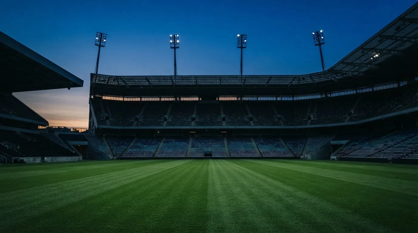 An empty football stadium with floodlight masts at dusk