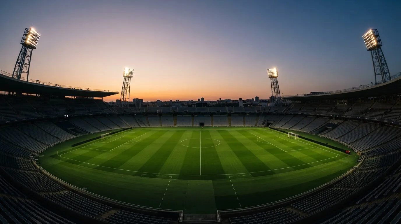 An empty football stadium with floodlight masts at dusk
