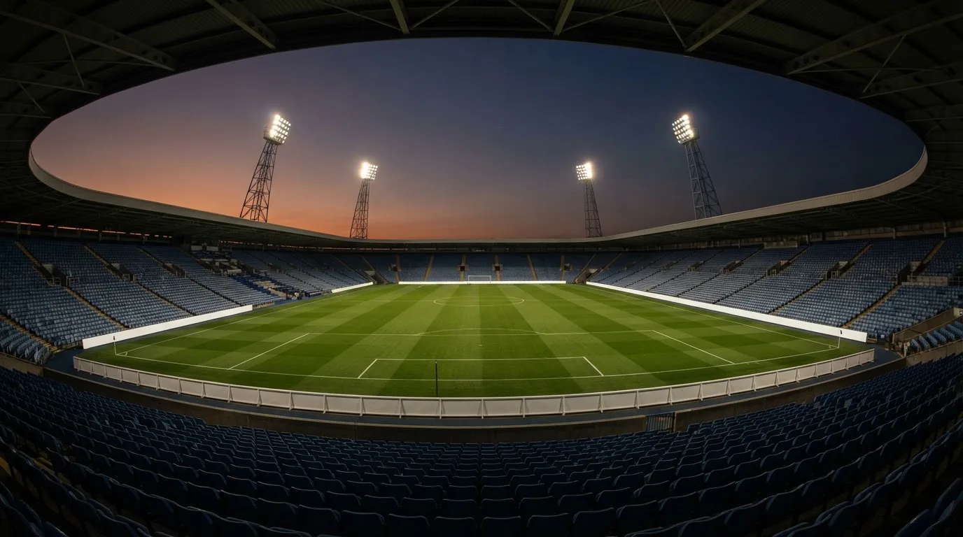 An empty football stadium with floodlight masts at dusk