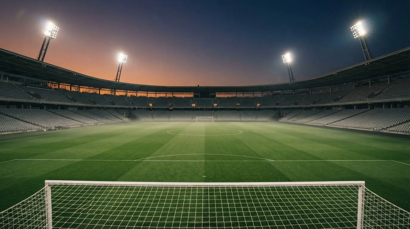 An empty football stadium with floodlight masts at dusk