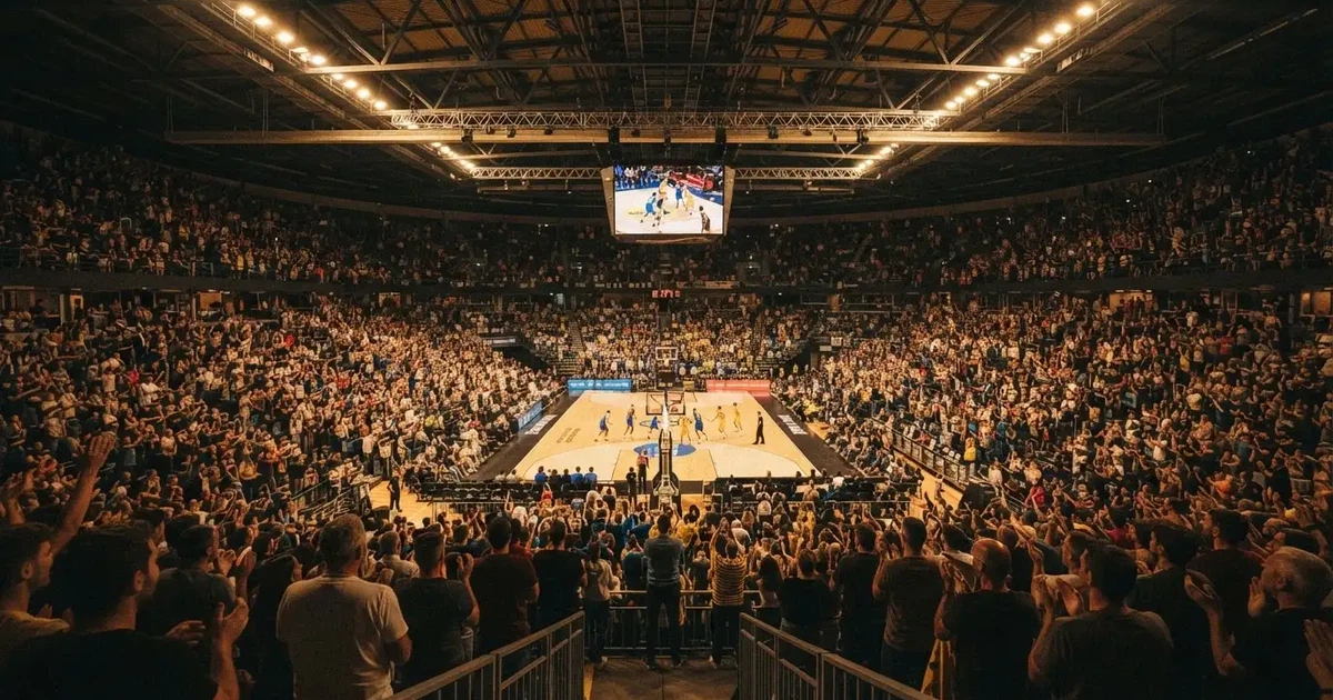 A packed sports hall under floodlights photographed from a long way off