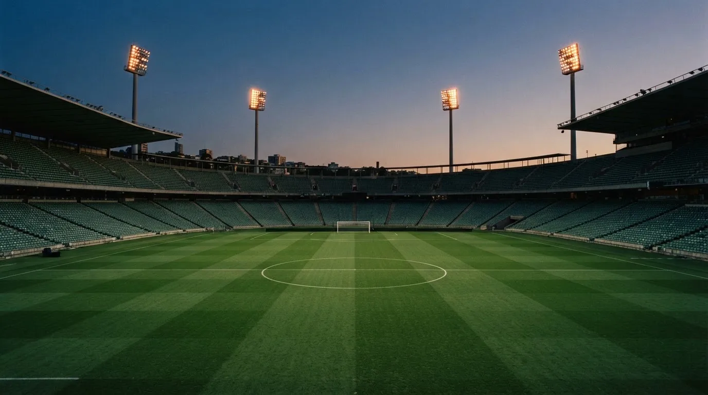 An empty football stadium with floodlight masts at dusk