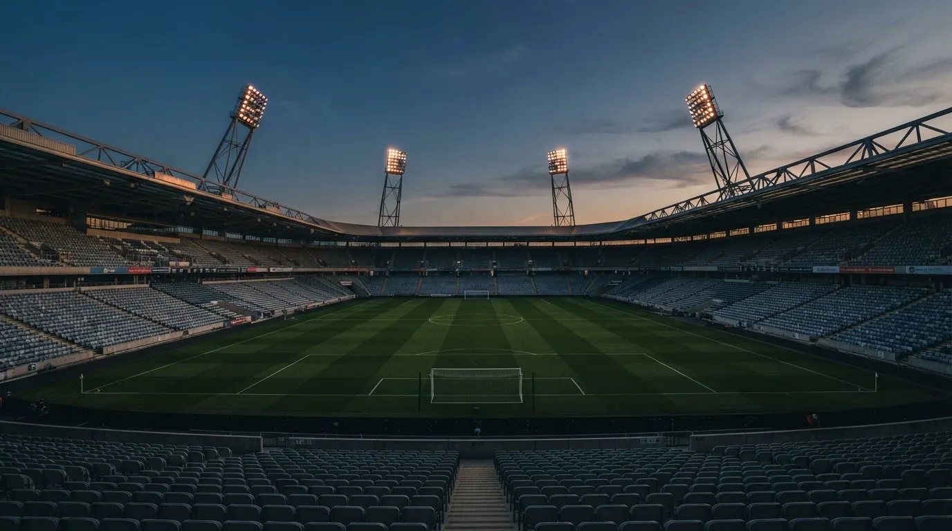 An empty football stadium with floodlight masts at dusk