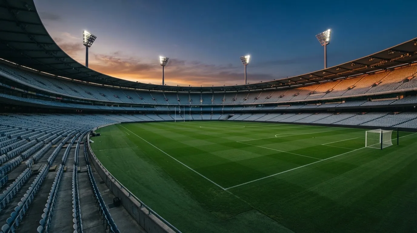 An empty football stadium with floodlight masts at dusk