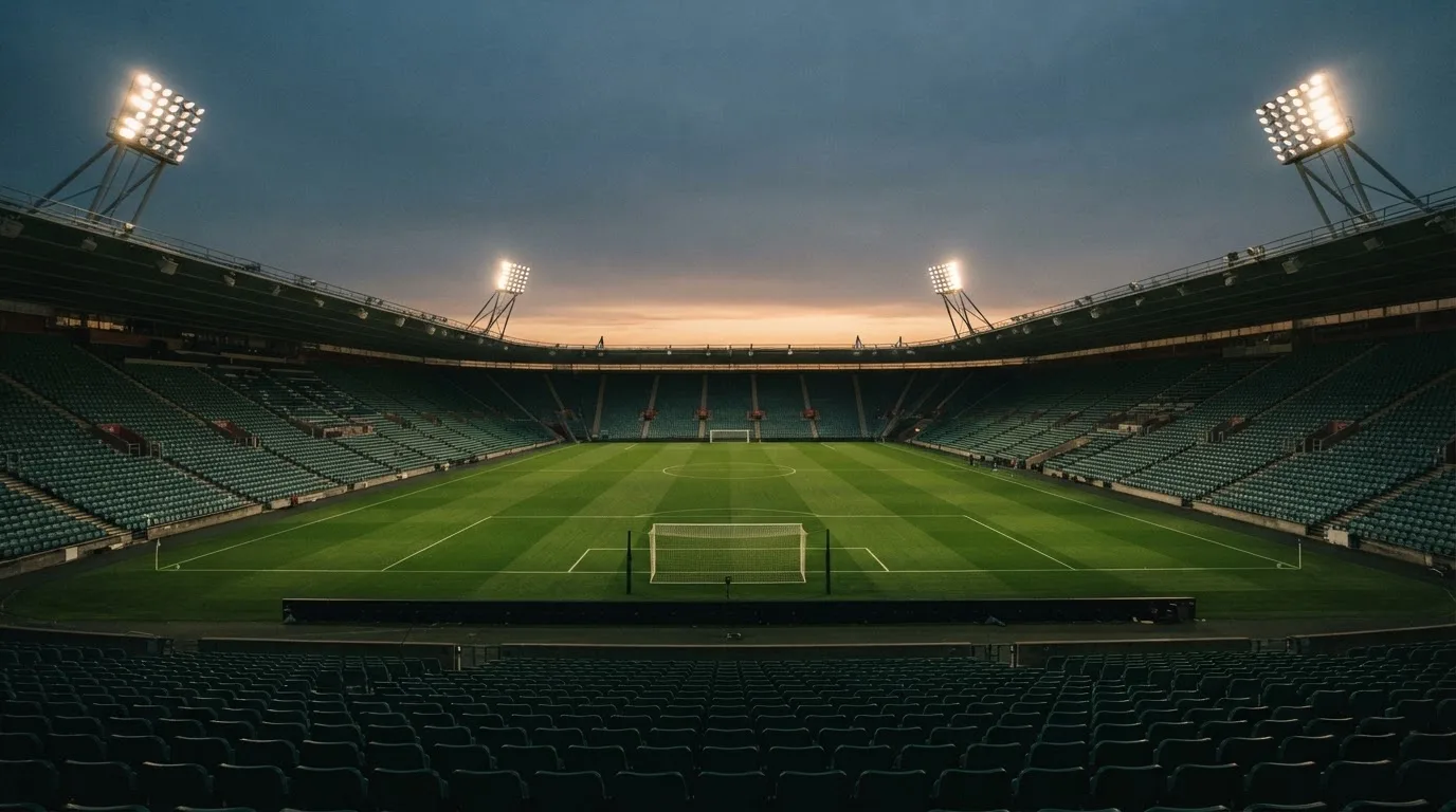 An empty football stadium with floodlight masts at dusk