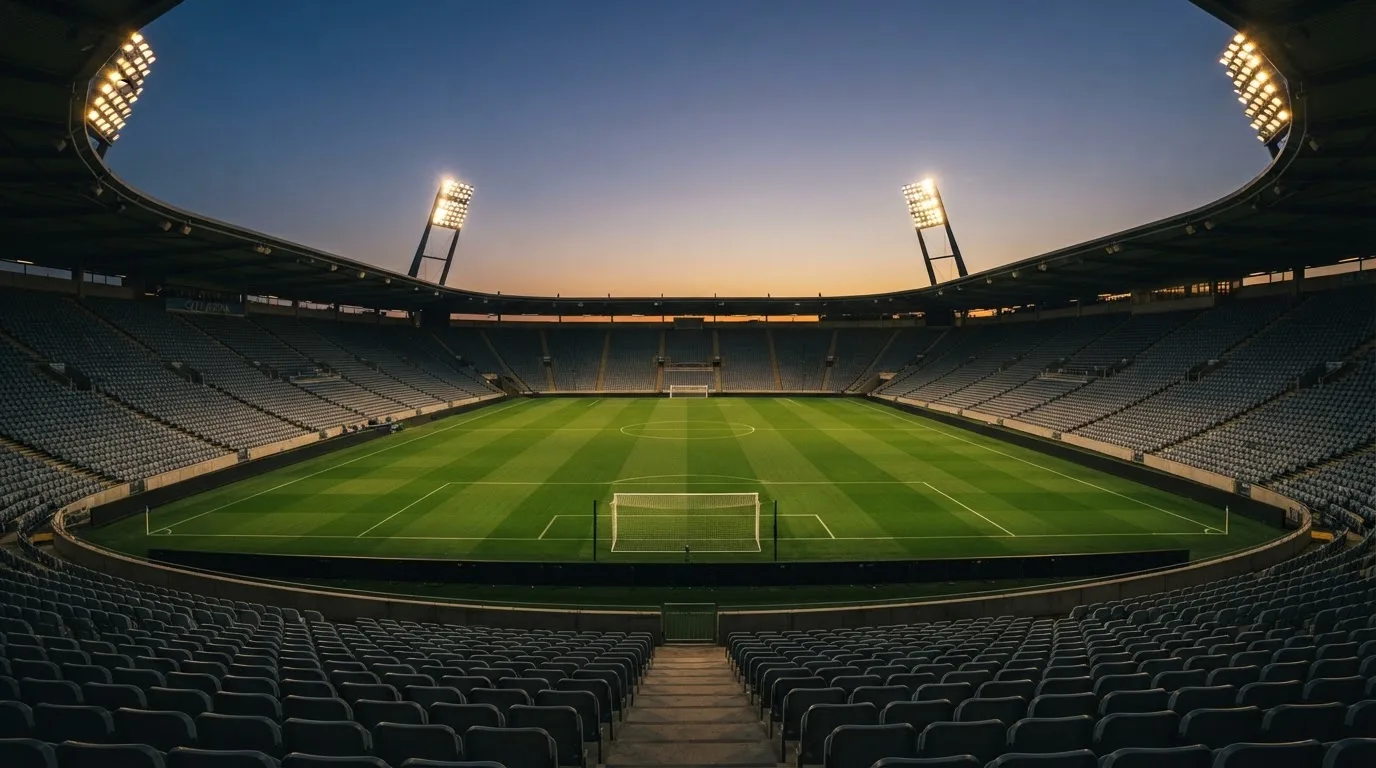 An empty football stadium with floodlight masts at dusk