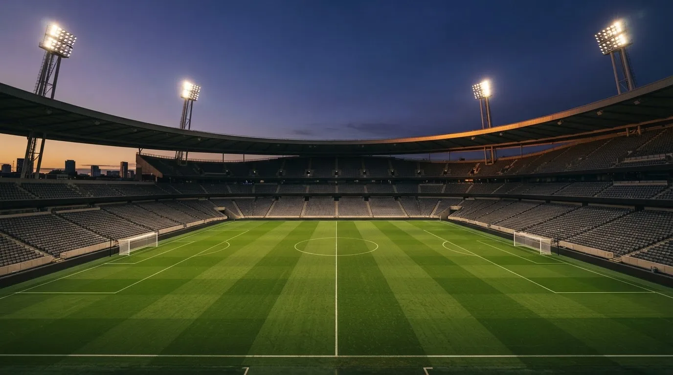 An empty football stadium with floodlight masts at dusk
