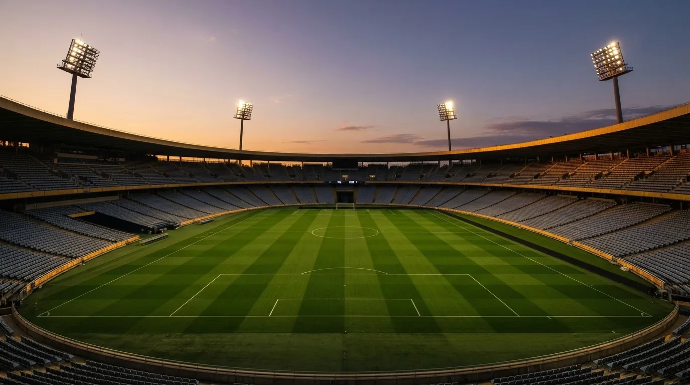 An empty football stadium with floodlight masts at dusk