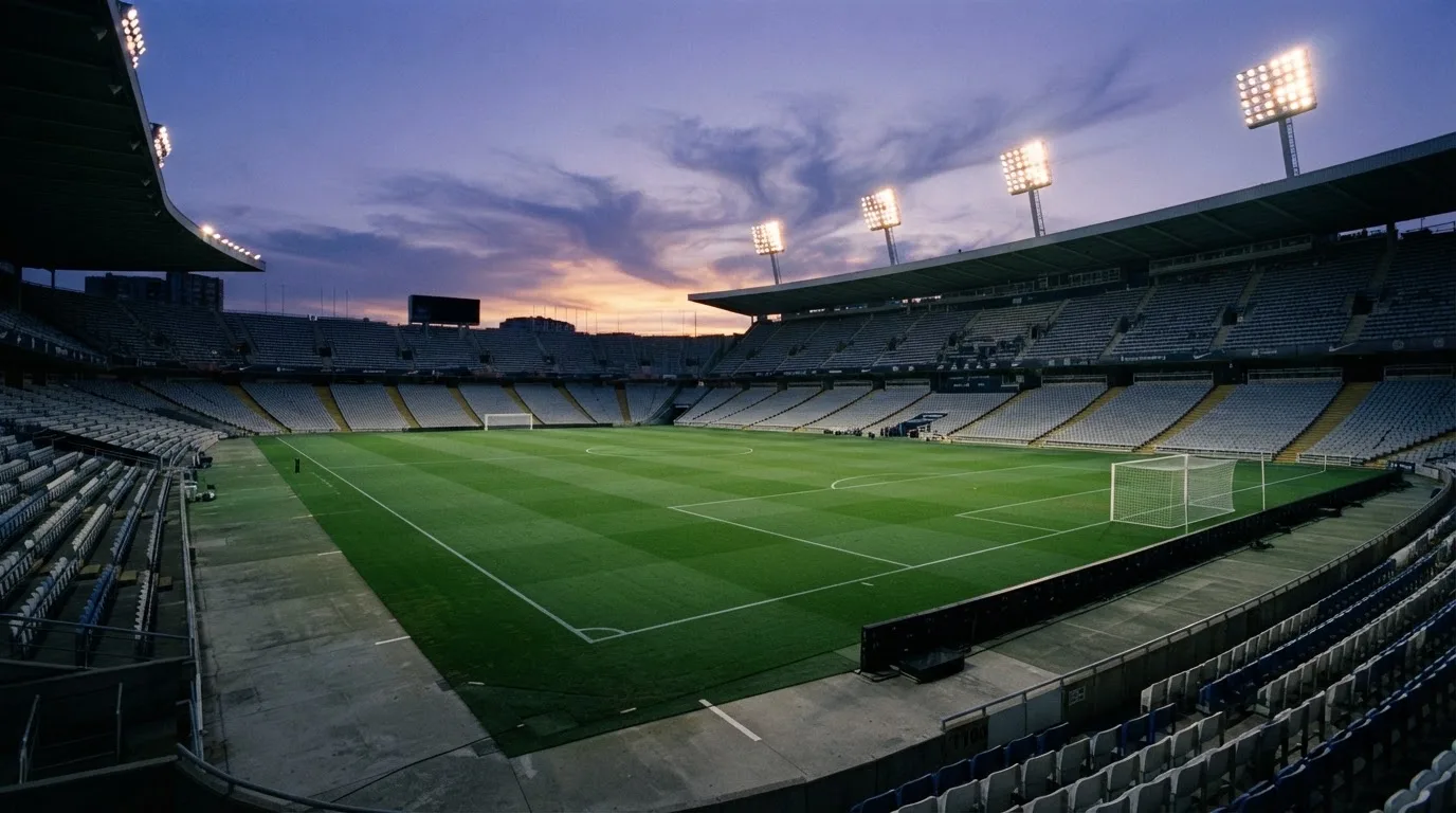 An empty football stadium with floodlight masts at dusk