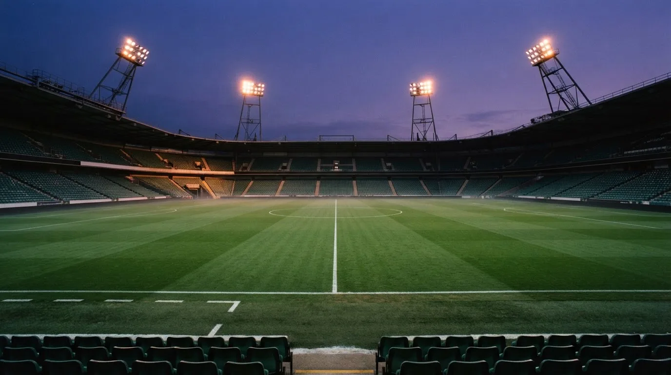 An empty football stadium with floodlight masts at dusk
