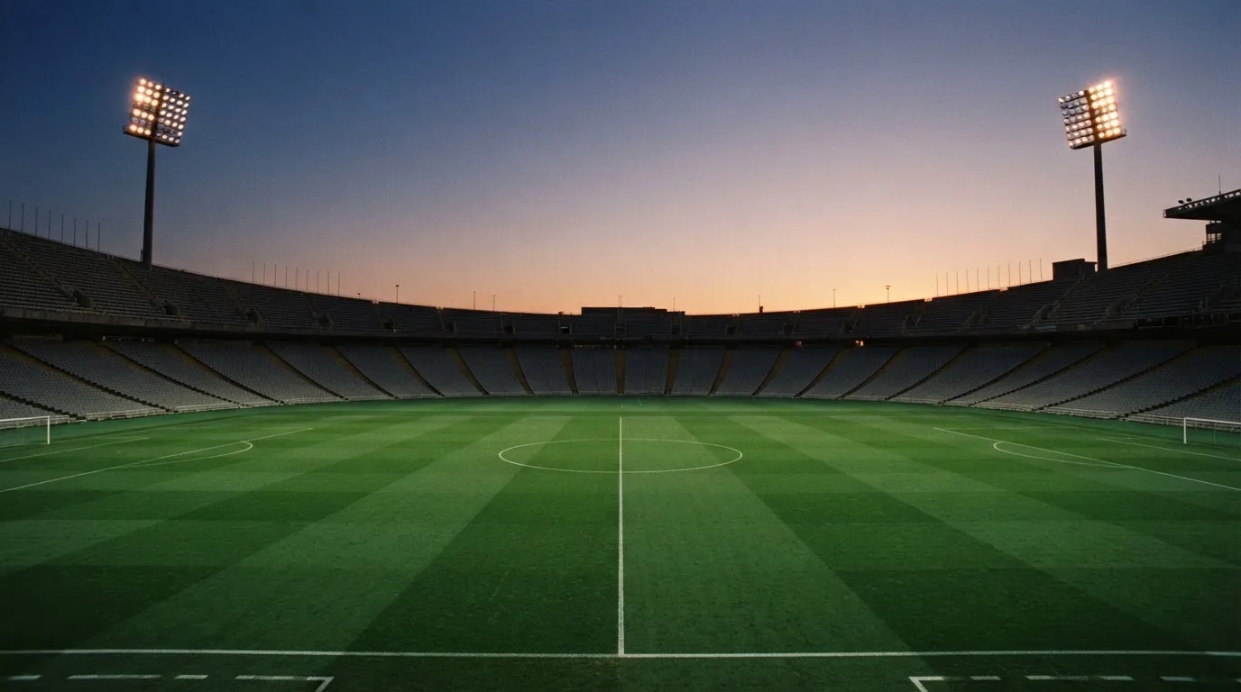 An empty football stadium with floodlight masts at dusk