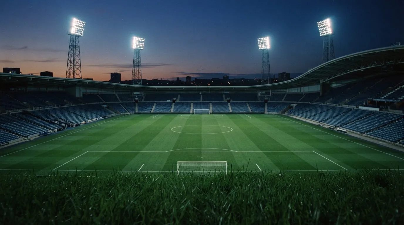 An empty football stadium with floodlight masts at dusk