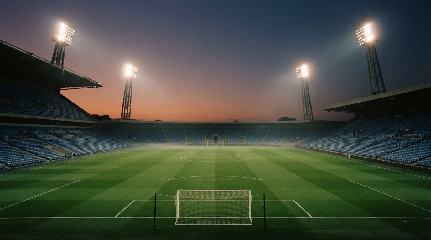 An empty football stadium with floodlight masts at dusk
