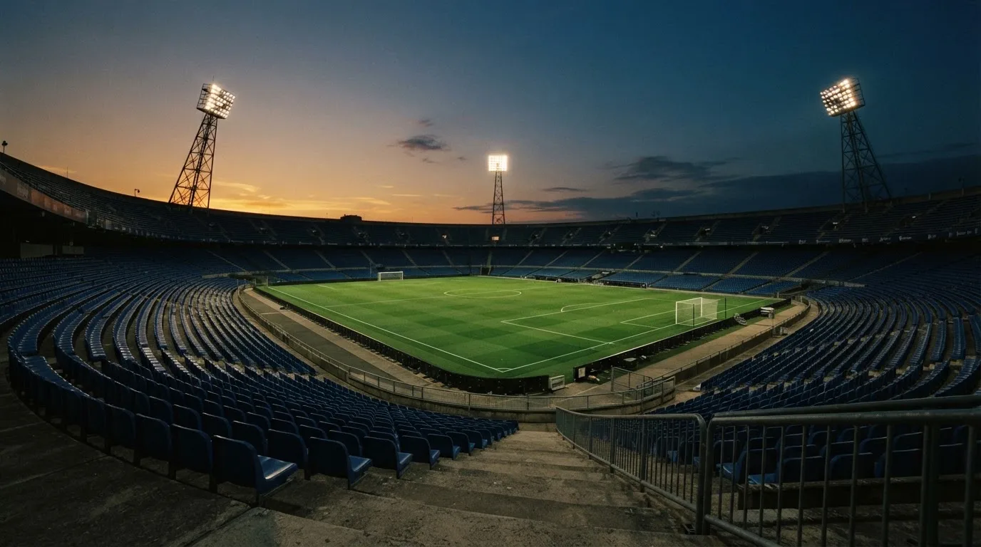 An empty football stadium with floodlight masts at dusk