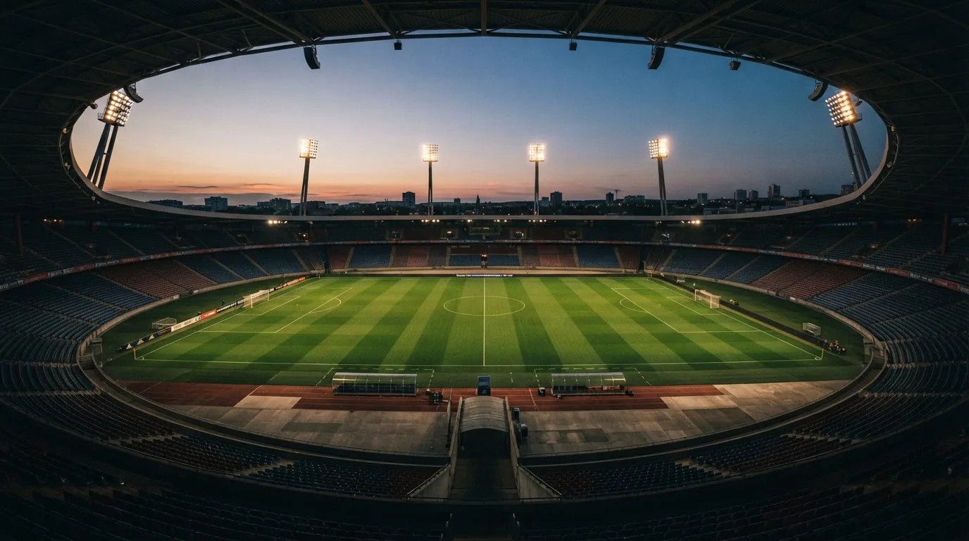 An empty football stadium with floodlight masts at dusk