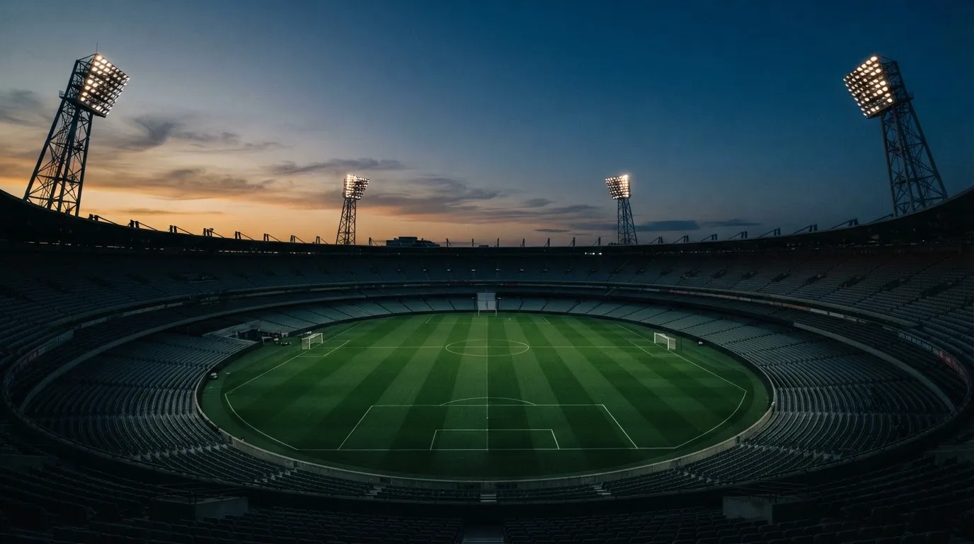 An empty football stadium with floodlight masts at dusk