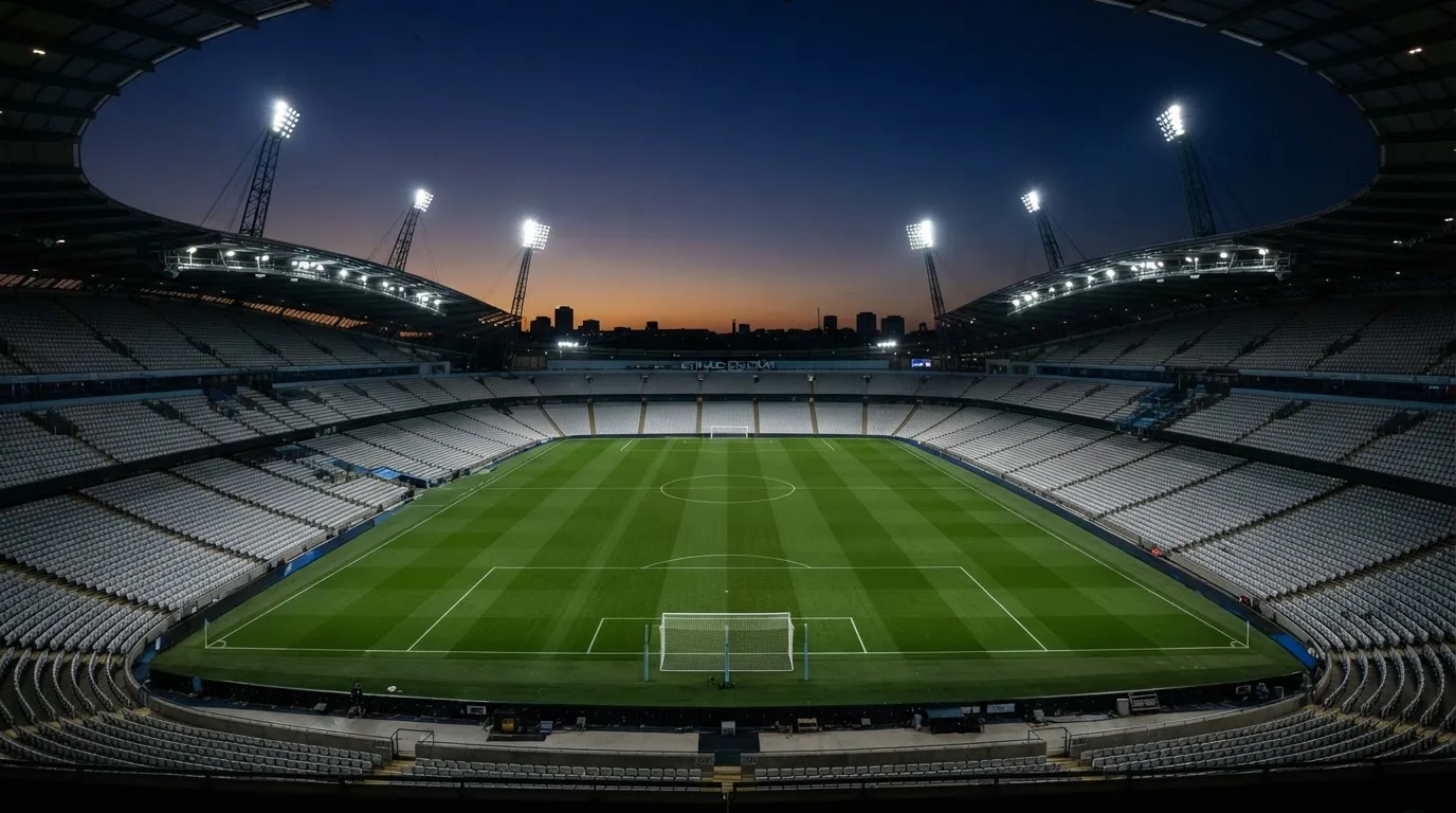 An empty football stadium with floodlight masts at dusk
