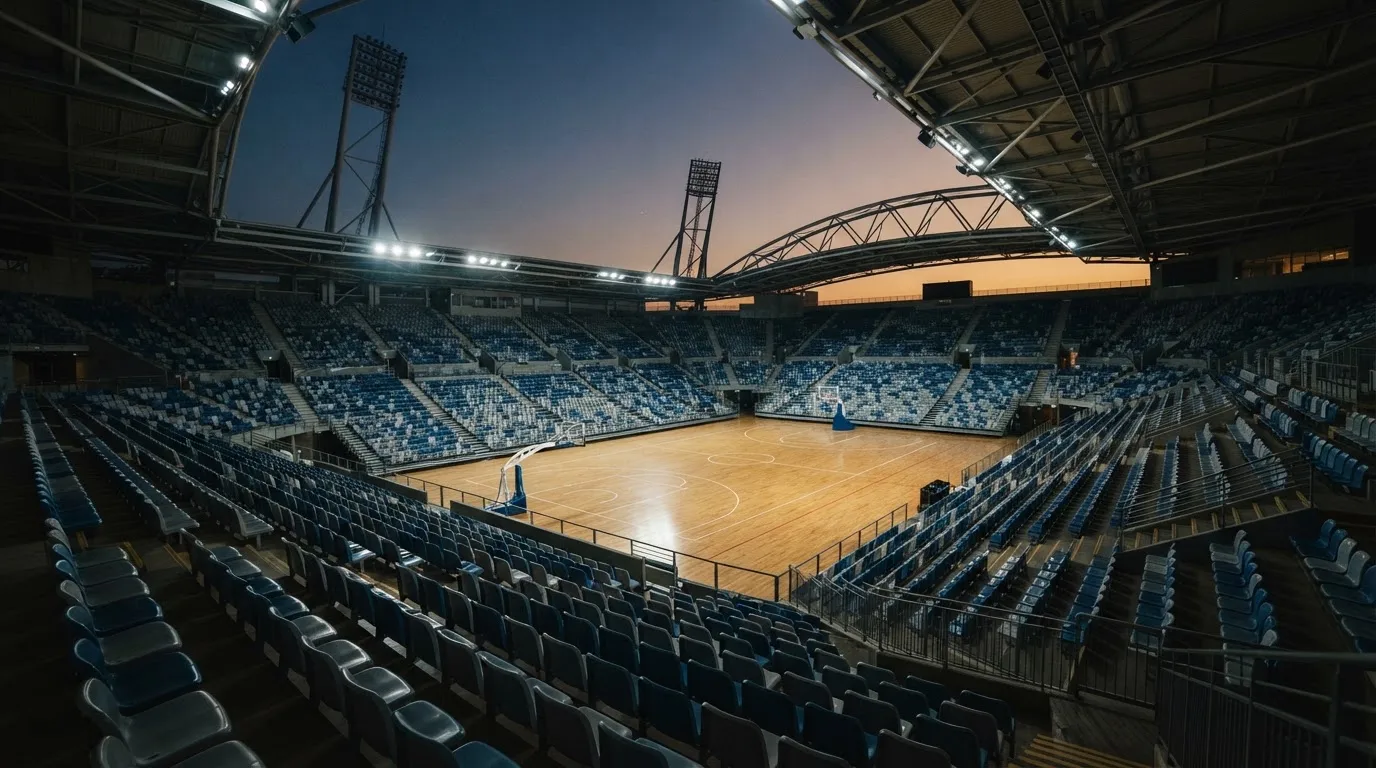 An empty football stadium with floodlight masts at dusk