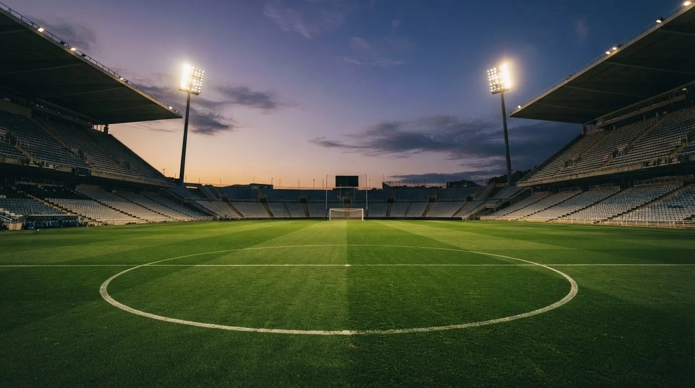 An empty football stadium with floodlight masts at dusk