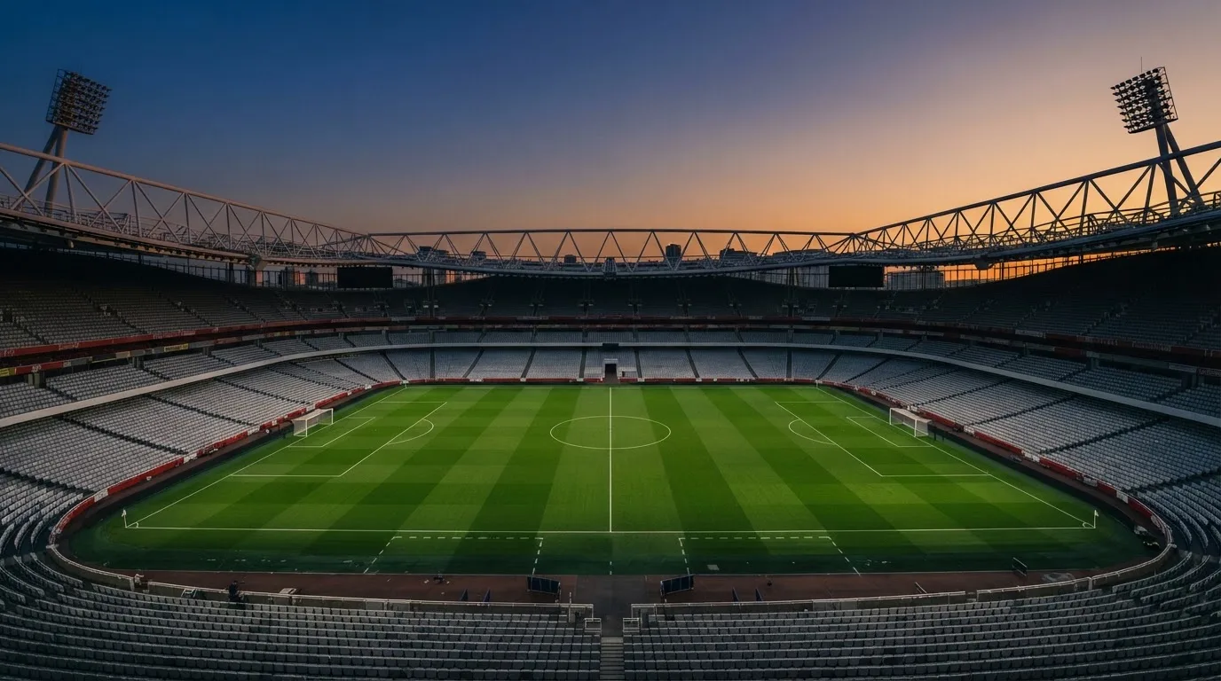 An empty football stadium with floodlight masts at dusk
