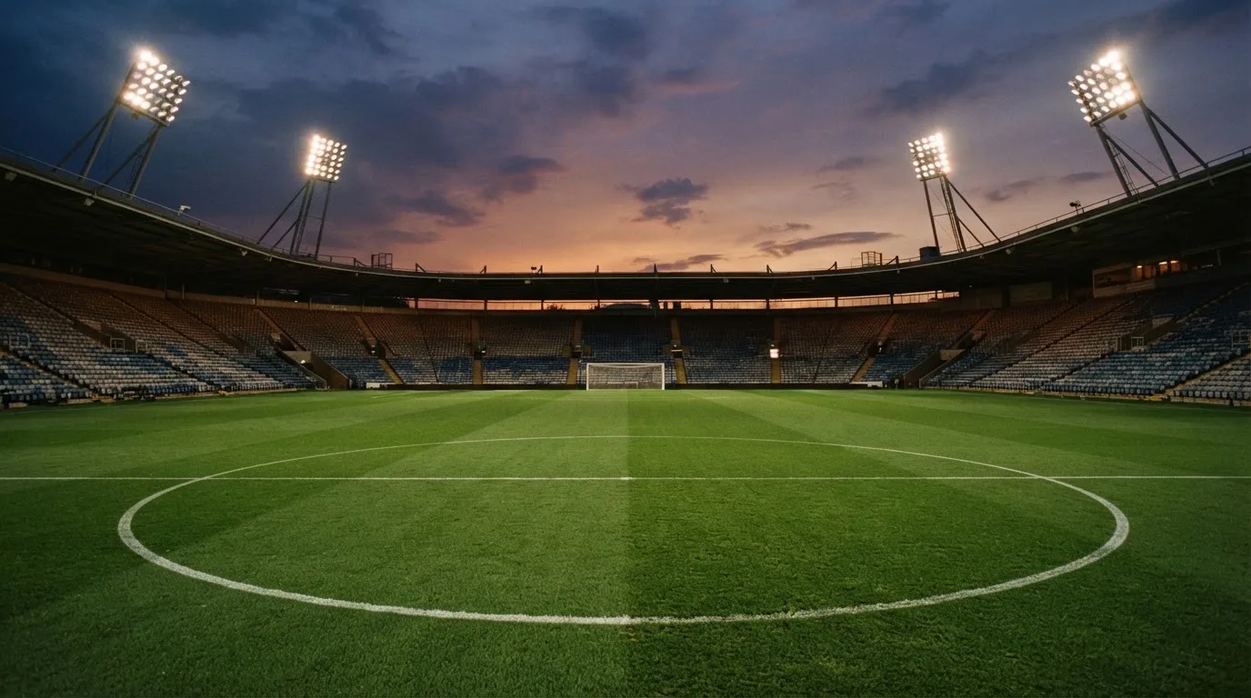 An empty football stadium with floodlight masts at dusk