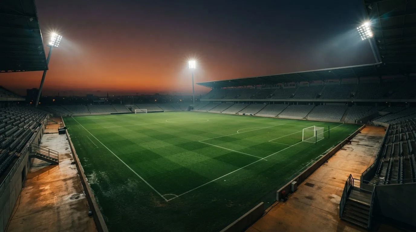 An empty football stadium with floodlight masts at dusk