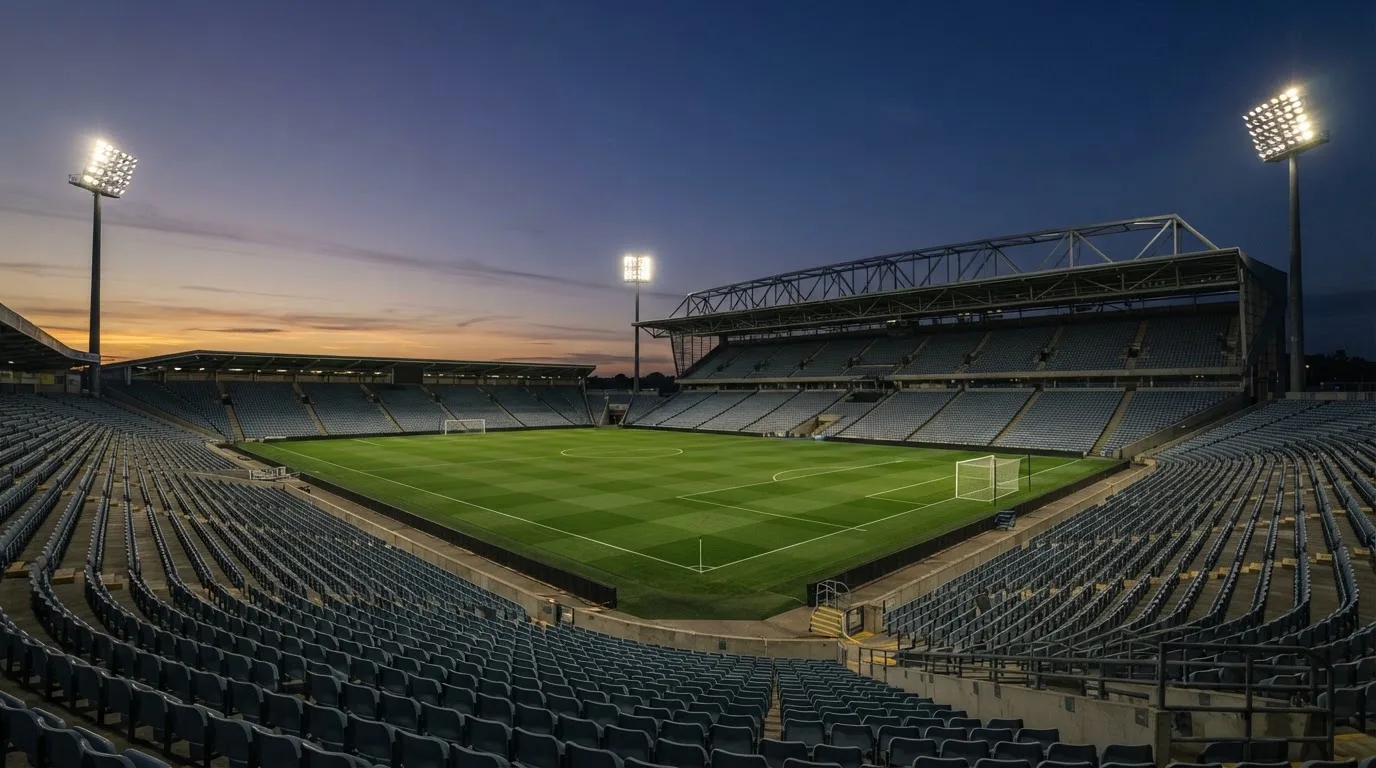 An empty football stadium with floodlight masts at dusk