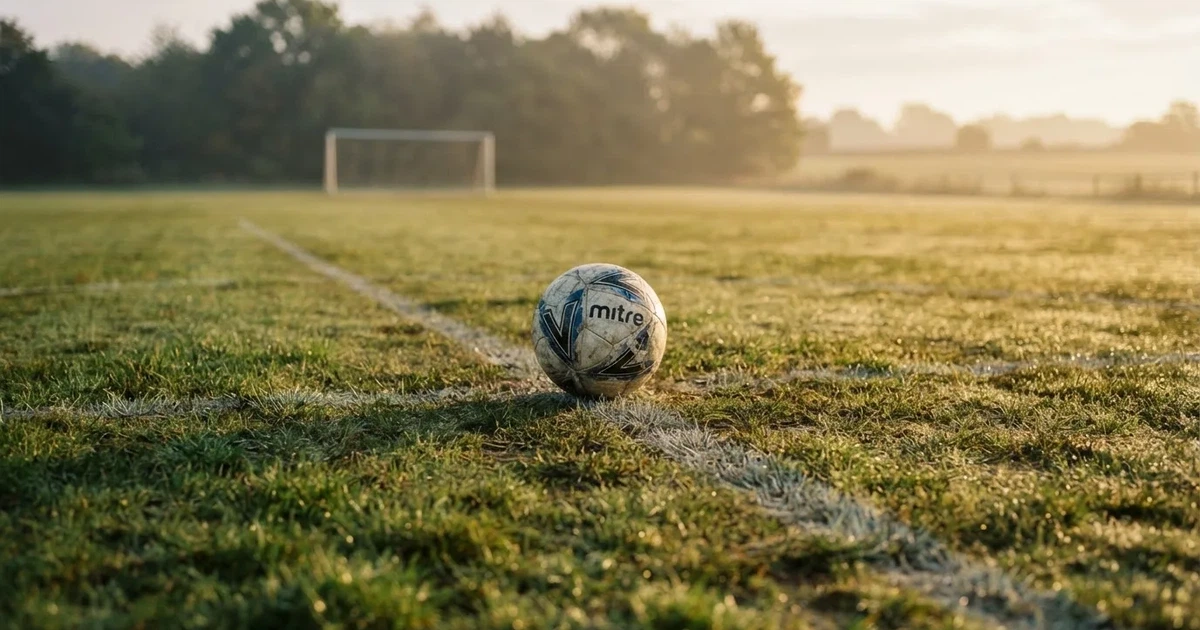 A ball on the centre spot of a grass pitch in morning light