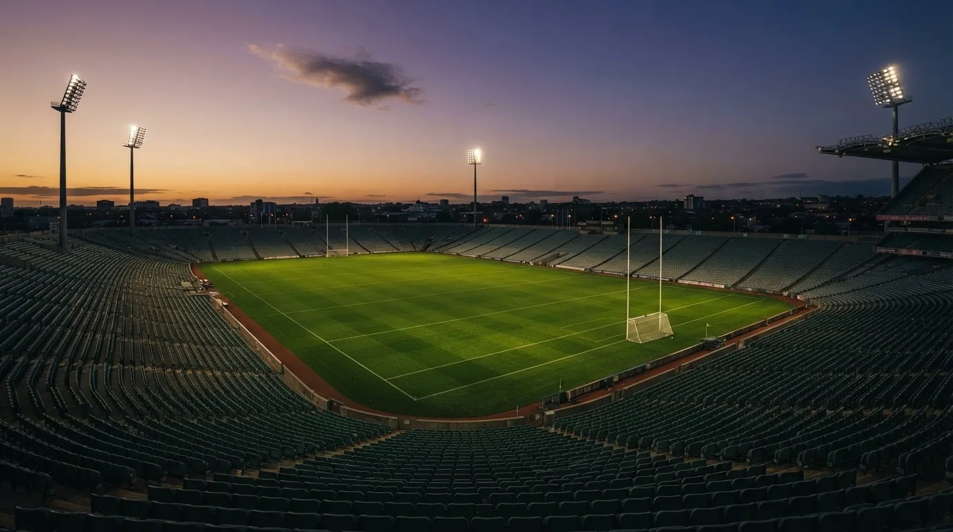 An empty football stadium with floodlight masts at dusk