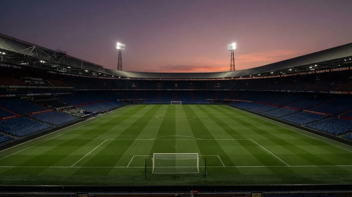 An empty football stadium with floodlight masts at dusk