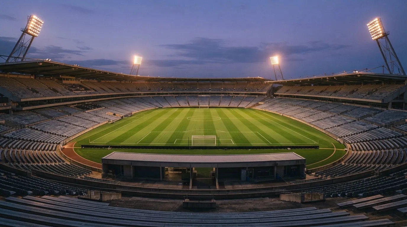 An empty football stadium with floodlight masts at dusk