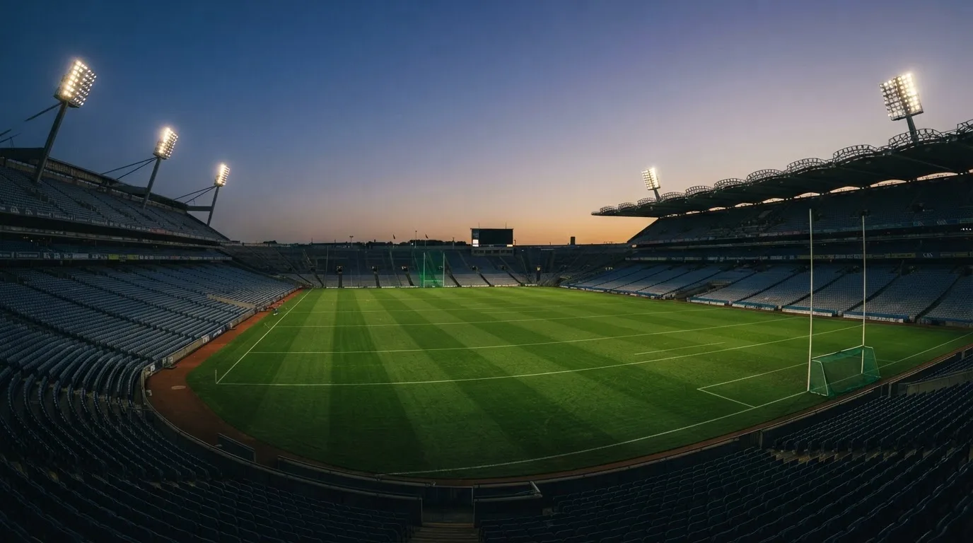 An empty football stadium with floodlight masts at dusk
