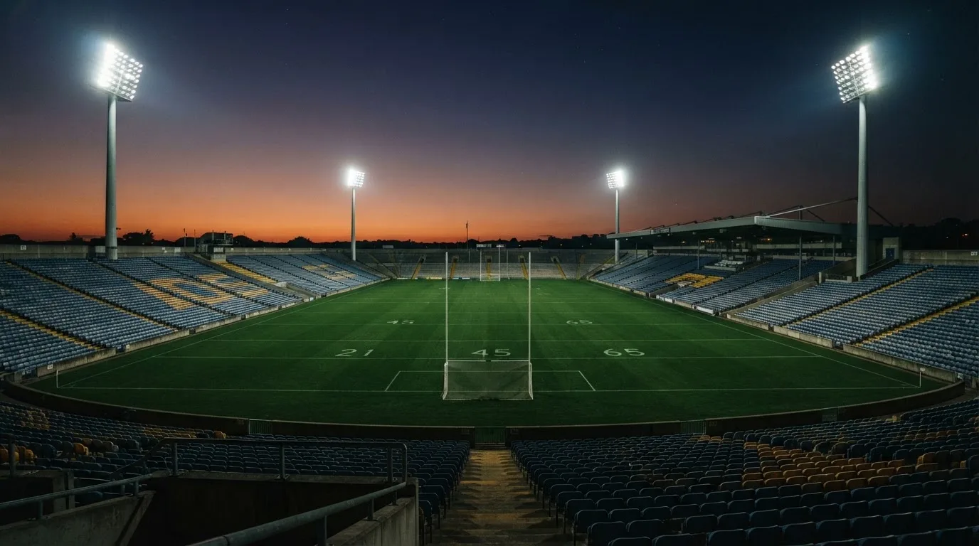 An empty football stadium with floodlight masts at dusk