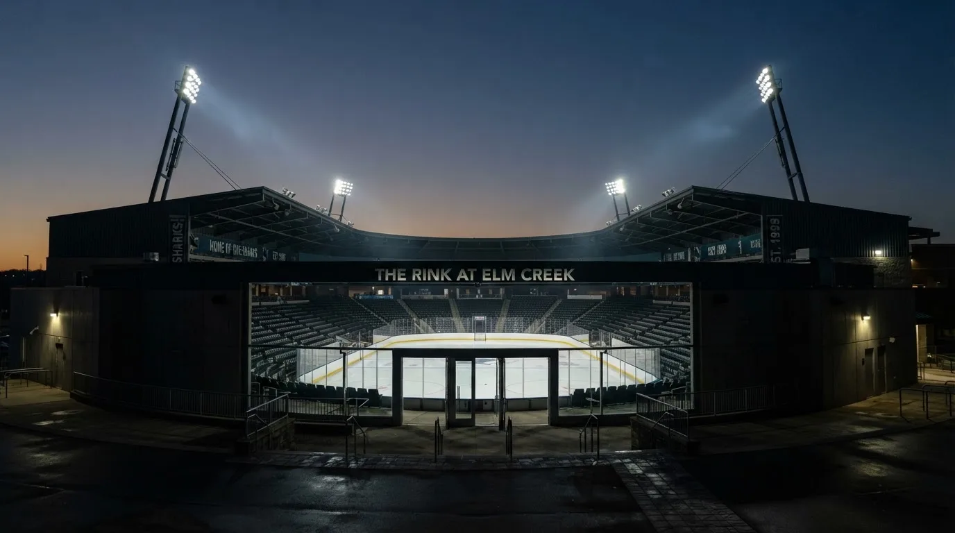 An empty football stadium with floodlight masts at dusk