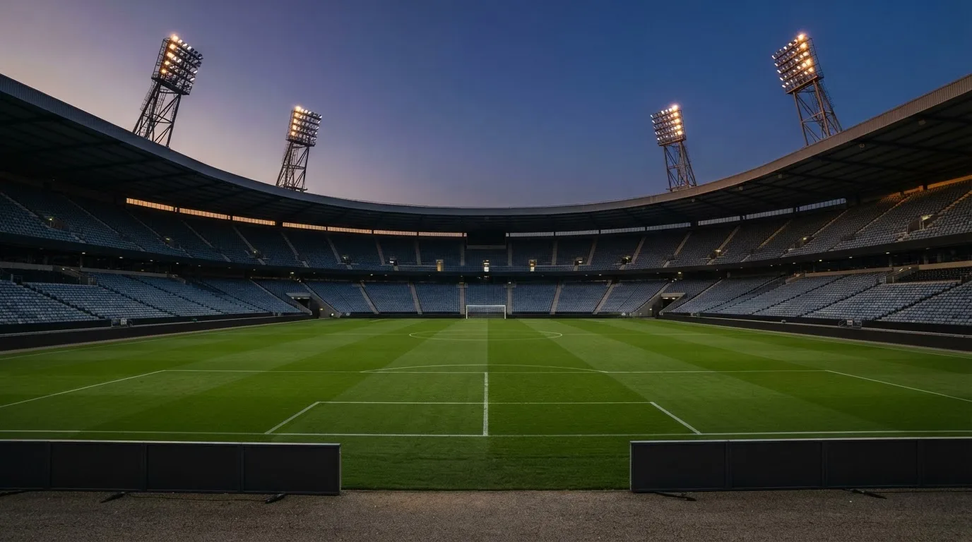 An empty football stadium with floodlight masts at dusk