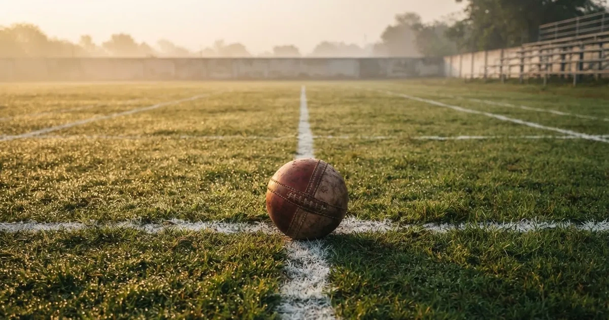 A ball on the centre spot of a grass pitch in morning light