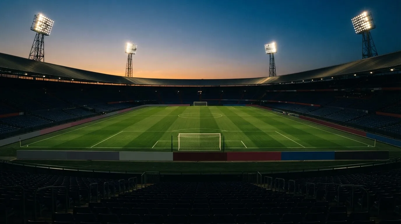 An empty football stadium with floodlight masts at dusk
