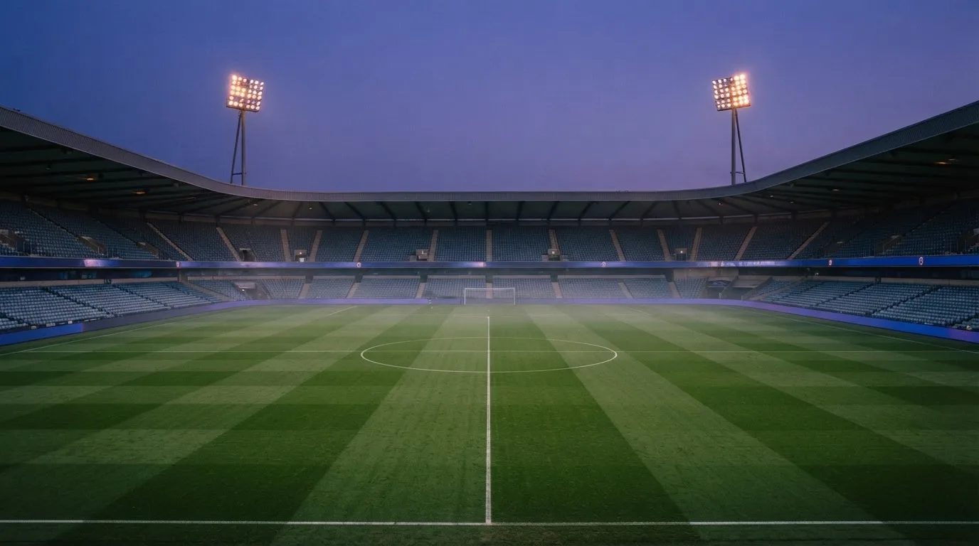 An empty football stadium with floodlight masts at dusk