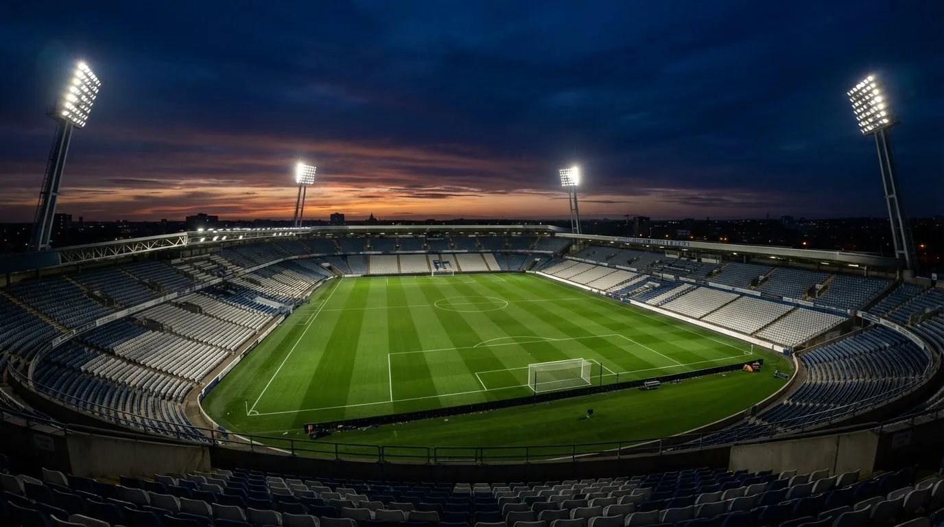 An empty football stadium with floodlight masts at dusk