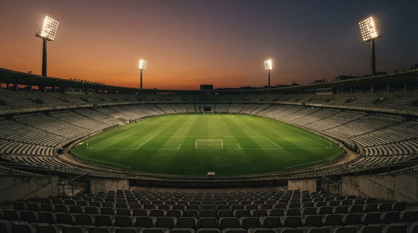 An empty football stadium with floodlight masts at dusk