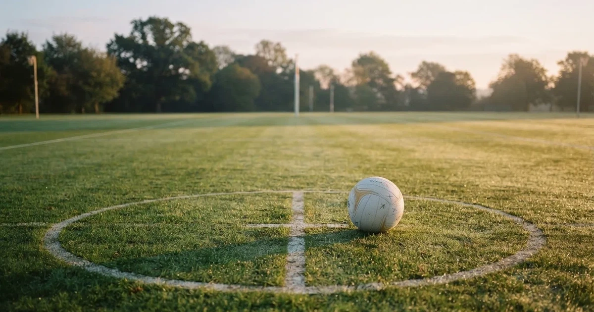 A ball on the centre spot of a grass pitch in morning light