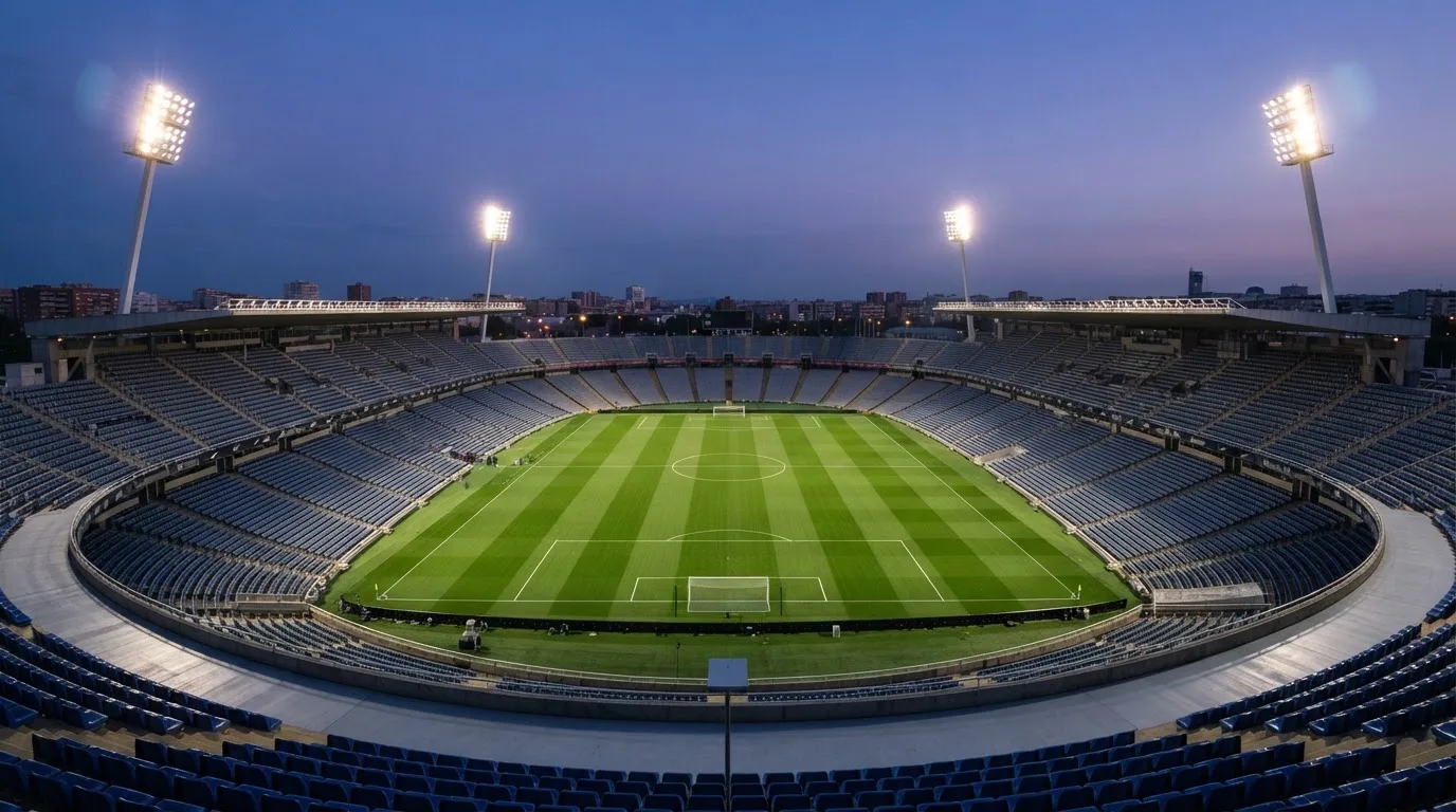 An empty football stadium with floodlight masts at dusk