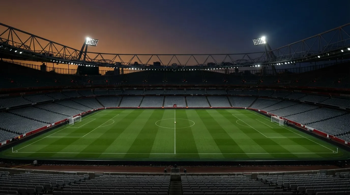 An empty football stadium with floodlight masts at dusk