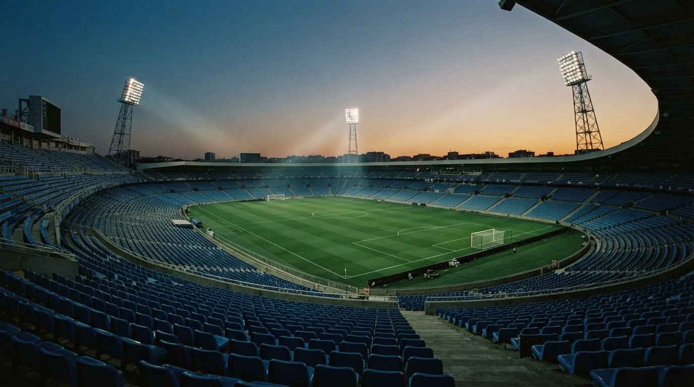 An empty football stadium with floodlight masts at dusk