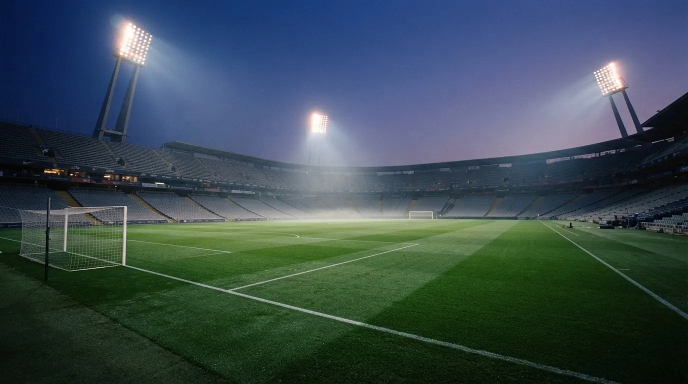 An empty football stadium with floodlight masts at dusk