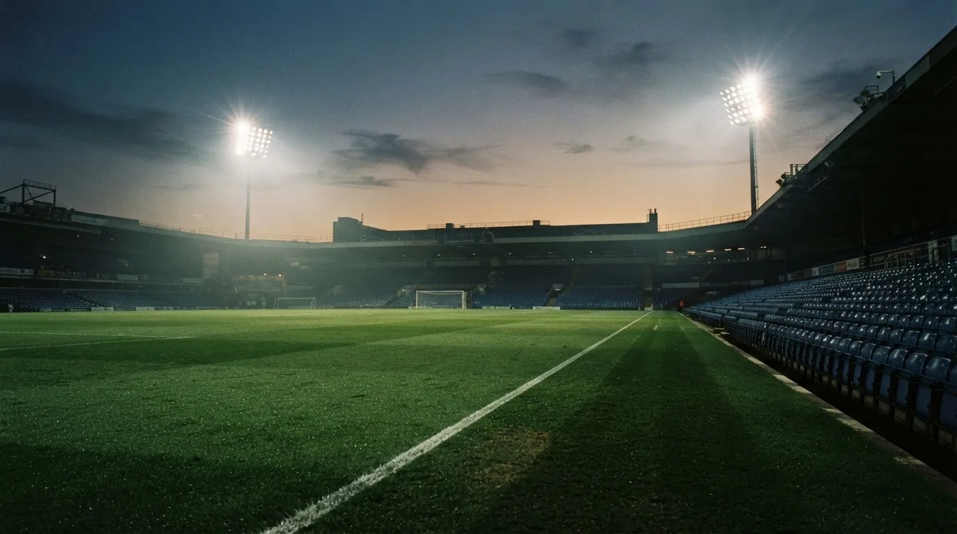 An empty football stadium with floodlight masts at dusk